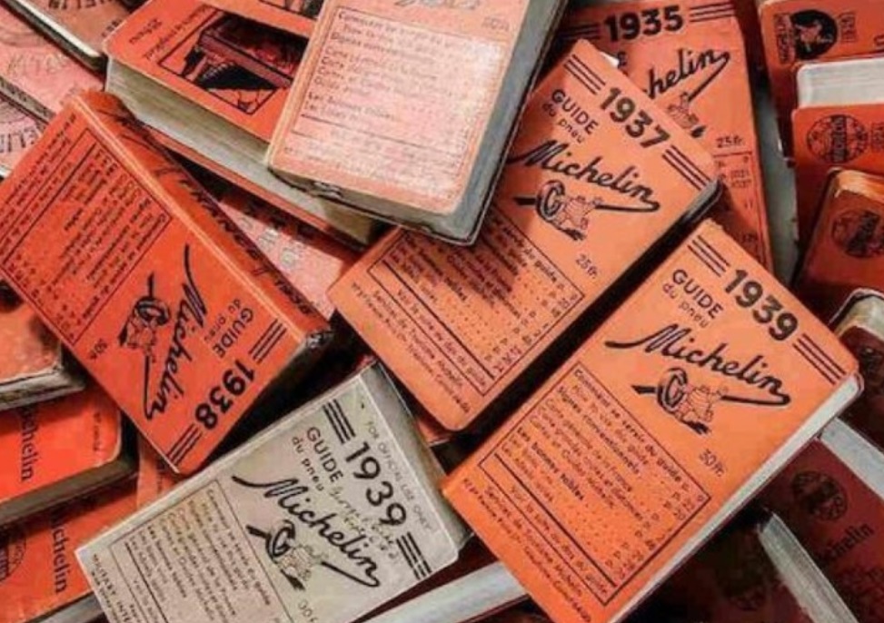 Livros vermelhos de capa dura do Guia Michelin da década de 30, empilhados de forma irregular
