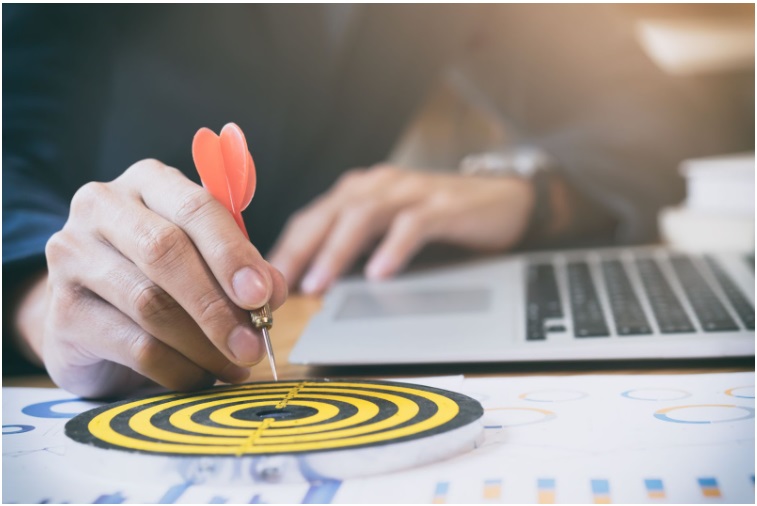 Mão segurando um dardo em diração a um alvo amarelo